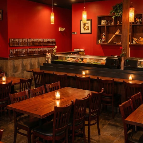Warmly lit Samurai Sushi dining room with red walls, wooden tables, and a sushi bar.