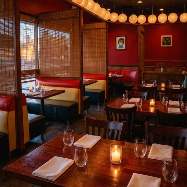 Cozy Samurai Sushi dining room with red walls, booth seating, wooden tables, and paper lanterns.