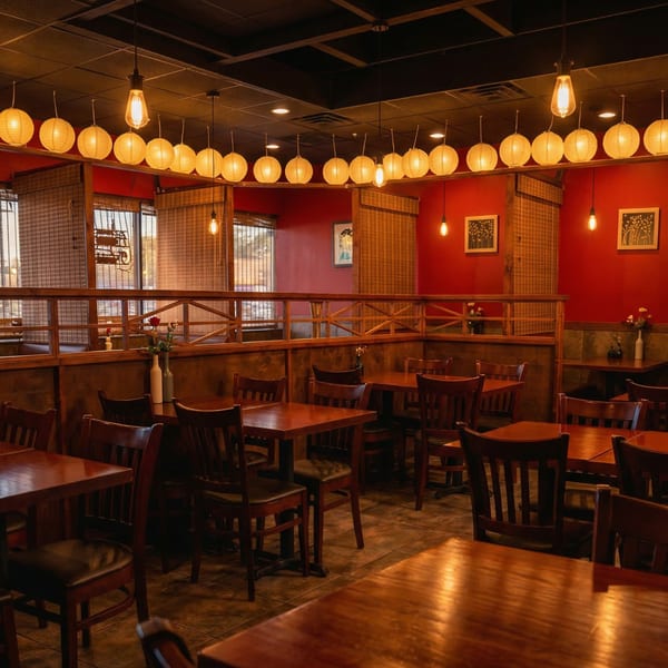 Warmly lit Samurai Sushi dining room with red walls, wooden tables, chairs, and paper lanterns.