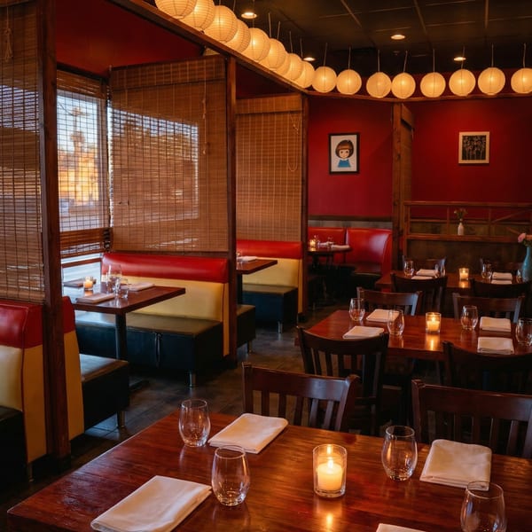 Cozy Samurai Sushi dining room with red walls, paper lanterns, and wooden tables set with candles.